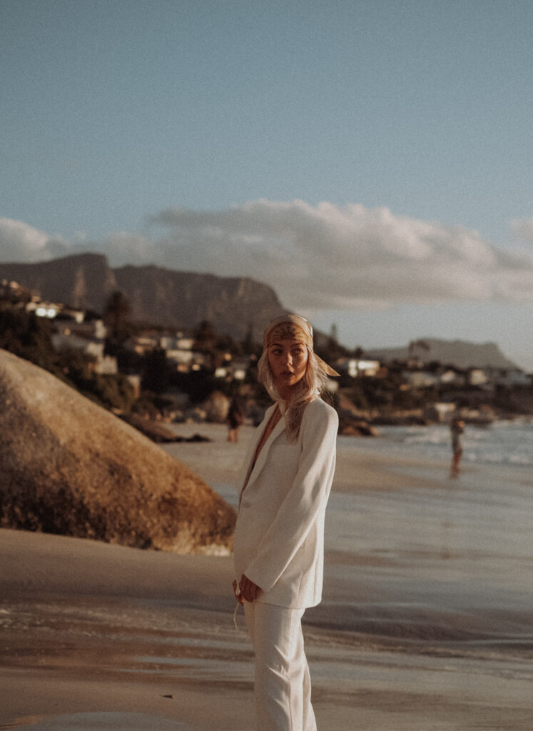 Digitale Nomadin Leni Gruber in weißem Anzug mit Kopftuch am Strand