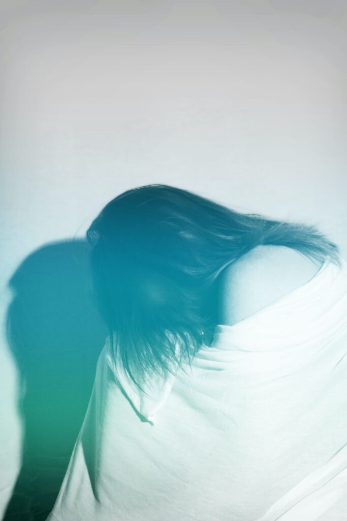 Frau sitzt mit Decke über dem Kopf am Boden