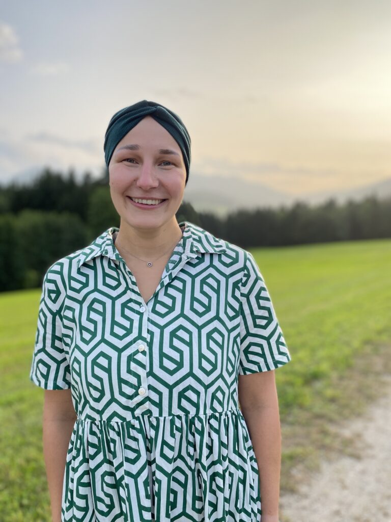 Jessica Brandner hat mit 23 alle Haare verloren. Sie trägt ein Haarband zu einem Sommerkleid.