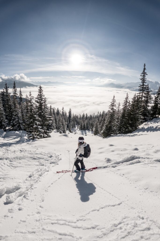 Eine Frau steht auf einer Skipiste und sieht in die Ferne