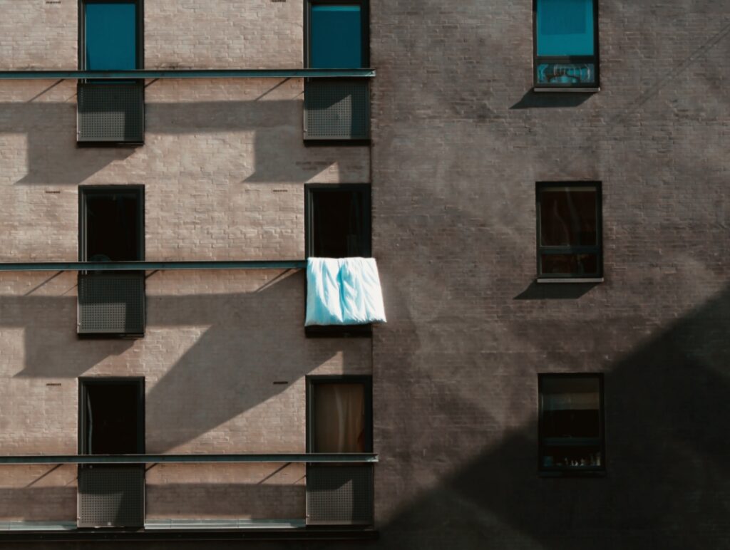 Eine Bettdecke wird über einem offenen Fenster ausgelüftet